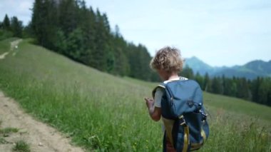 Dağlarda yürüyüş yapan küçük bir çocuk Sırt çantasıyla doğa yürüyüşü yapıyor
