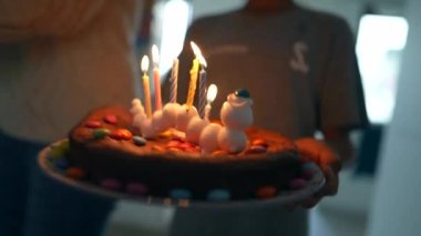 Doğum günü pastasını mumlarla taşıyan çocuk.