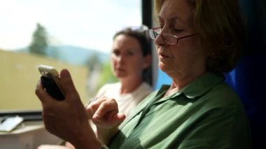 Yetişkin kızıyla trenle seyahat eden son sınıf öğrencisi bir kadın.