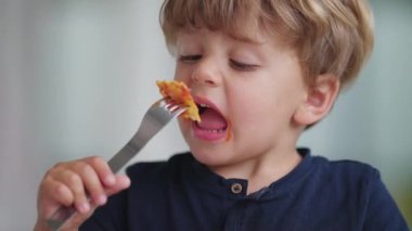 Makarna yiyen küçük çocuk sıcak yemek yiyor.