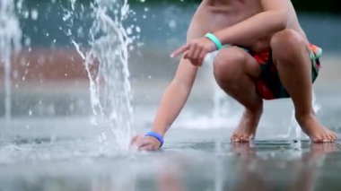 Çocuk musluk çalıp su basıncını arttırıyor.