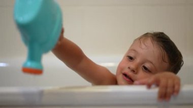 Küçük çocuk banyo küvetinde oynuyor.