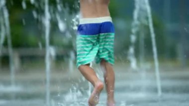 Çeşmede koşan çocuk yaz günü eğleniyor.