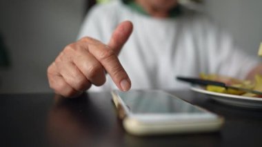 İnternette gezinen yaşlı bir kadın parmaklarıyla ekrana dokunuyor