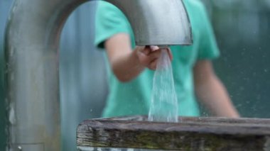 Çocuk musluk çalıp su basıncını arttırıyor.
