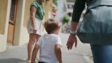 Küçük çocuğun arkası Avrupa sokaklarında yürüyor anne ve ailesi