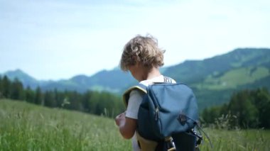 Dağlarda yürüyüş yapan küçük bir çocuk Sırt çantasıyla doğa yürüyüşü yapıyor