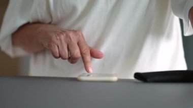 Cep telefonu ekranına parmağıyla mesaj yazan yaşlı bir kadın.