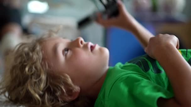 Ένα Μικρό Αγόρι Παίζει Παιχνίδι Ξαπλωμένο Στο Πάτωμα — Αρχείο Βίντεο