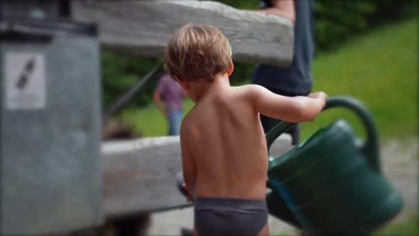 小さな男の子保持散水缶外に庭で下着を身に着けている — ストック動画