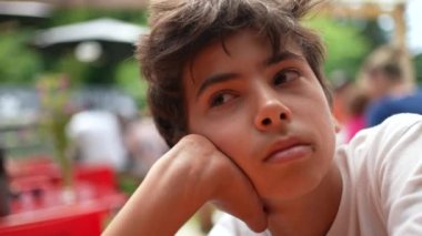 Düşünceli bir yüzü olan genç bir çocuk.