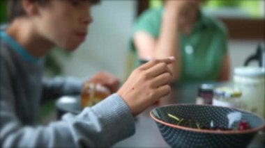 Çocuk sabah kahvaltısında kaseden kiraz meyvesi alıyor.