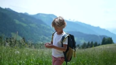 Düşünceli küçük bir çocuk İsviçre dağlarında dışarıda yürüyor.