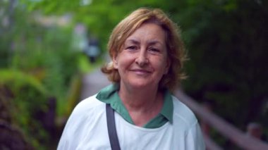 Dışarıda parkta yürüyen mutlu bir son sınıf kadın portresi.