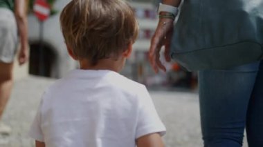 Küçük çocuğun arkası Avrupa sokaklarında yürüyor anne ve ailesi