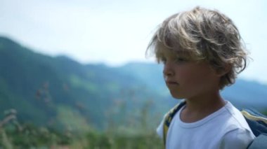Çocuk dağlarda yeşil yolda yürüyor.