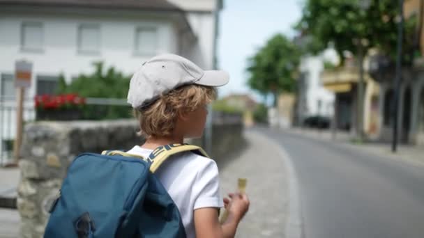 バックパックを持って学校に行く若い男の子の通りを歩く — ストック動画