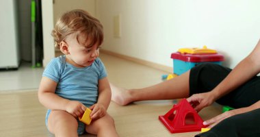 Adorable baby playing with puzzle pieces toys indoors with mom