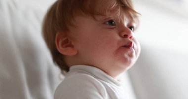 Baby grabbing blueberry and putting snack into mouth. Adorable one year old child eating food