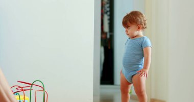 Baby development walking at home indoors. One year old toddler infant learning to walk