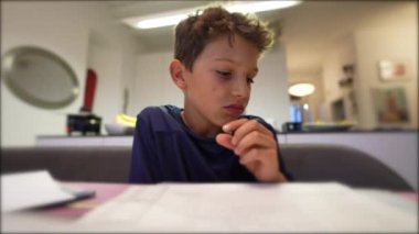 Kid doing homework holding pen writing notes
