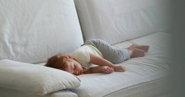 Candid baby sleeping on sofa in the afternoon nap. Cute infant toddler asleep