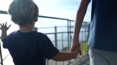 Children holding hands, brother holding little sibling hand walking together outside