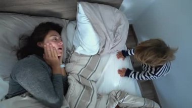 Authentic family morning bed, mother and child toddler waking up