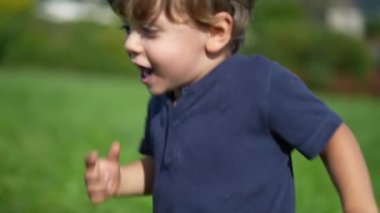 Küçük çocuk çimenlerin üzerinde kardeşine doğru koşuyor. Kardeşine rastlıyor.