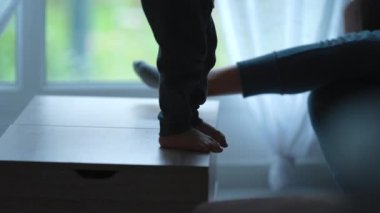 Aktif küçük çocuk evdeki kanepede zıplıyor. Çocuk kanepenin üstüne atlar.