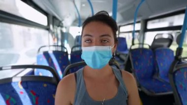 Otobüsün içinde maskeli bir kadın cerrahi maske takıyor.