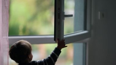 Little boy closing window. Child closes open window