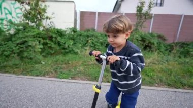 Küçük çocuk üç tekerlekli scooter kullanıyor.