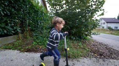 Küçük çocuk dışarıda üç tekerlekli scooter sürüyor, mutlu çocuk scooter kullanıyor.