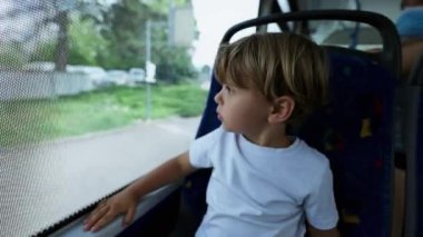 Otobüs koltuğunda oturan yolcu çocuk pencereden dışarı bakıyor.