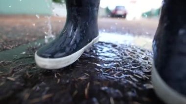 Kid jumps into puddle of water wearing boots