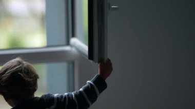 Child closing window. Toddler closes window