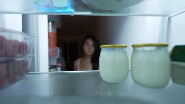 空腹の女性は冷蔵庫を開き 冷蔵庫の中に健康的なスナックを選ぶ — ストック動画