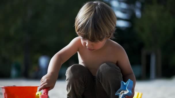 Маленький Хлопчик Грає Лопатою Відром Зовні Пісочниці — стокове відео
