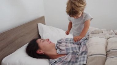 Anne, çocuk uyandığında yatakta yatar ve günlük rutine başlar.