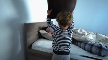 Toddler playing pillow fight with mother in morning waking up parent with pillow