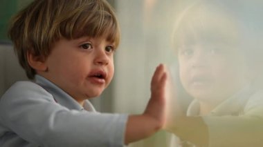 Çocuk pencereden dışarı bakarak trenle seyahat ediyor. Yolculuktaki küçük çocuğun sanatsal klibi.