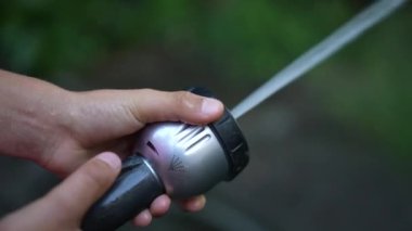 İtfaiye hortumunu tutan, suyu sulayan bahçenin yakınına.