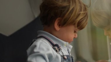 Trenin camına yaslanan çocuk hayal kuruyor, düşünceli bebek.
