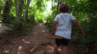 Doğada oynayan çocuk orman yolunda koşuyor.