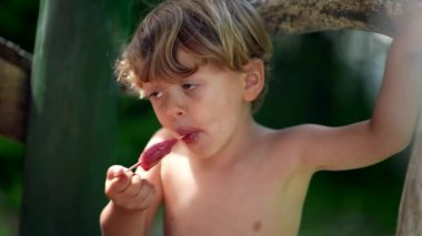 Çocuk sıcak yaz gününde dondurma yiyor. Tatlı tatlı yiyor.