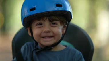 Bisiklet kaskı takan mutlu küçük bir çocuk portre suratlı el çırpıyor.
