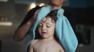 Anne banyodan sonra çocuk saçlarını havluyla kurutuyor.