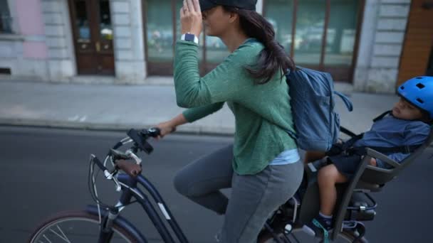 後部座席で寝ている子供と都市部の通りで母に乗る自転車 — ストック動画