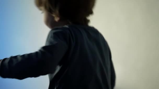幸せな小さな男の子遊びますホームジャンプオンソファソファ — ストック動画